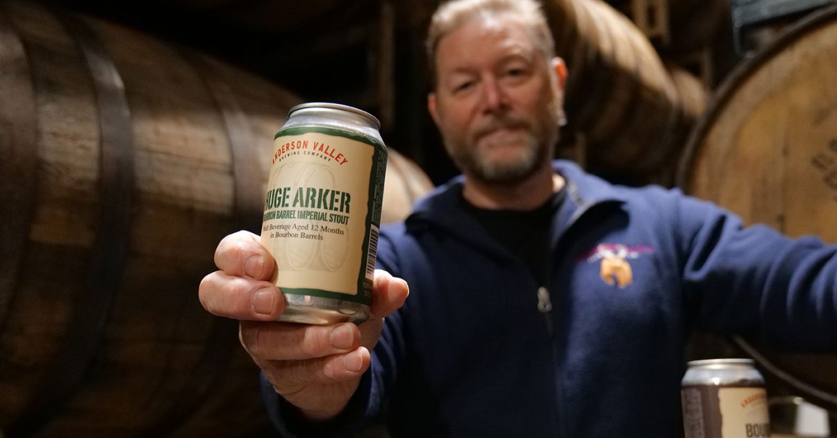 man holding out beer in barrel house