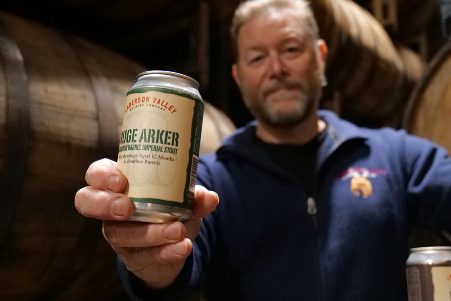 man holding out beer in barrel house